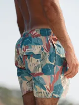 Short de baño para hombre con estampado de hojas en tonos celeste, verde, beige y coral. Tiene elástico en la cintura, tres bolsillos (dos laterales y uno trasero), tela con 10% spandex de secado rápido con doble costura de seguridad e interior con mesh hipoalergénico.
