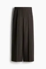 Pantalón ancho color marrón oscuro, de tiro alto con cierre, botón y corchetes ocultos, bolsillos al bies y bolsillos atrás decorativos. Piernas amplias con pliegue adelante y atrás.