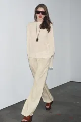Sweater color crema de tejido de punto liso, con cuello barco y mangas anchas que se estrechan hacia la muñeca.