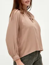 Blusa blanca de mangas largas con cuello fruncido y lazo.