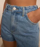Short de jeans azul claro, corte slim, con trabillas en la cintura, bolsillos delanteros y traseros, y apliques de brillos en los laterales.