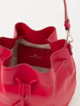 Bolso tipo bucket de cuero rojo con correa larga ajustable y detalles dorados.