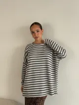 Sweater de punto a rayas horizontales blancas y negras, de corte holgado y mangas largas.