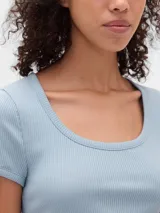 Remera de manga corta ajustada al cuerpo, color gris claro, con tejido acanalado (rib). Presenta un escote redondo amplio.