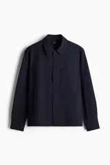 Sobrecamisa azul marino de corte recto, con cuello inglés, cierre frontal con botones, mangas largas con puños abotonados, dos bolsillos de parche en el pecho y canesú en la espalda.