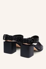 Sandalia de cuero vacuno negra con tiras cruzadas y tachas metálicas. Taco ancho de 6,5 cm.