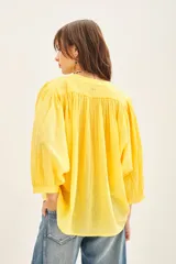 Camisa amarilla de algodón con corte amplio, cuello redondo y mangas 3/4 con puños elásticos.