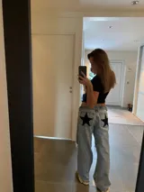 Pantalón de jean gris oscuro con corte recto y bolsillos traseros con apliques de estrellas rojas.