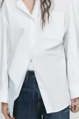 Camisa negra de cuello solapa y manga larga amplia. Tiene un bolsillo de parche en el delantero, detalle de pliegues y cierre frontal con botones.