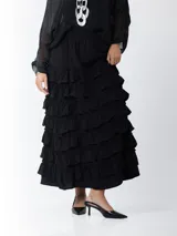 Falda larga negra con cintura elástica y múltiples volados horizontales.