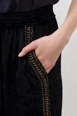 Pantalón palazzo negro de terciopelo con cintura elástica y detalle de bordado dorado en los laterales.