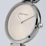 Reloj análogo Jacques Lemans modelo Milano para dama, con caja redonda de acero plateado y esfera color champagne/beige. Posee marcadores de hora en relieve y agujas plateadas. La correa es de malla milanesa de acero plateado.