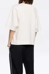 Remera color blanco hueso de corte cuadrado, con cuello redondo y mangas cortas amplias.