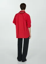 Camisa roja oversize de algodón con cuello camisero, manga larga abotonada, bolsillo de parche en el pecho y cierre frontal con botones.