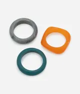 Set de tres brazaletes rígidos de resina en diferentes colores: gris marmolado, naranja traslúcido y verde esmeralda. El brazalete naranja tiene forma cuadrada con bordes redondeados.