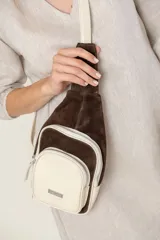 Mochila bandolera de cuero color marrón chocolate y detalles en color crema. Tiene dos bolsillos con cierre y correa regulable.