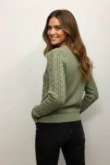 Sweater color crema de punto trenzado, con cuello redondo y mangas largas.