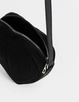 Bandolera negra en forma de corazón, confeccionada en cuerina acolchada con pespuntes verticales. Tiene correa larga regulable y cierre superior.