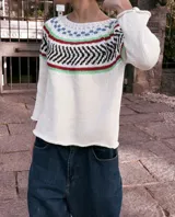 Sweater tejido a mano en hilo de algodón color crudo, con cuello redondo y mangas 3/4 con volados. Presenta un diseño geométrico en el pecho con detalles en negro, rojo, verde y azul.