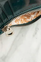 Billetera de cuero vegano color petróleo con cierre y compartimentos para tarjetas.
