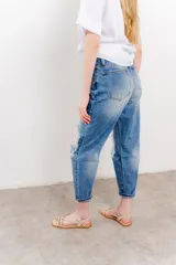 Jean azul de tiro medio y calce relaxed, con roturas amplias y desflecadas.