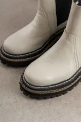 Botas de cuero color gris claro, con suela gruesa y detalles en negro.