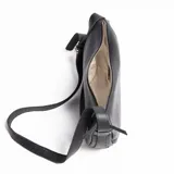 Bandolera negra de cuero graneado con correa ajustable que rodea toda la cartera. Tiene forma de media luna con bordes redondeados.