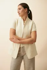 Chaleco color beige, entallado, con solapa, bolsillos plaqué y terminaciones envivadas.