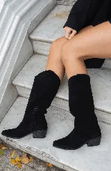 Botas texanas de caña media color negro, confeccionadas en cuero gamuzado, con puntera fina y taco bajo. Presentan detalles de costuras decorativas en el empeine y laterales.