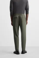 Pantalón color arena de corte recto, confeccionado en tejido elástico. Cuenta con cintura elástica ajustable con cordón, bolsillos laterales y bolsillos de vivo en la parte trasera.