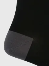 Calcetines largos negros con rayas horizontales grises en la parte superior y logo de Hush Puppies bordado.