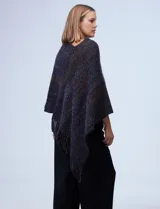 Poncho de tejido suave, color crudo con hilos multicolores que generan un efecto jaspeado en tonos pastel (rosa, celeste, lila). Presenta un diseño asimétrico con cuello redondo y terminación en flecos largos en el ruedo.