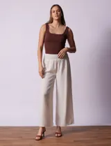 Pantalón largo de poliéster color beige con rayas verticales, pretina ancha elastizada en punto smock y pierna ancha.