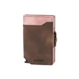Billetera doble de cuero marrón con detalles en rosa. Cuenta con doble caja de aluminio con sistema de deslizamiento para tarjetas, clip para billetes y espacio adicional para documentos.