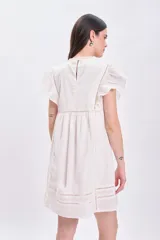 Vestido corto color crudo, de estilo boho, con bordados y mangas cortas con volados.