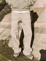 Pantalón jean color arena, de corte amplio, tiro alto y diseño de carpintero con múltiples bolsillos.