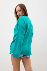 Sweater oversize color verde con diseño de manga larga y ribetes en los extremos.