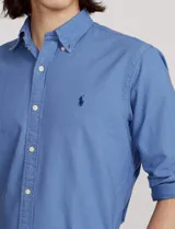 Camisa blanca de corte clásico, confeccionada en tejido oxford de algodón. Presenta cuello button-down, manga larga con puños abotonados y logo bordado en el pecho.
