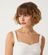 Blusa cropped blanca de lino con escote en V y tirantes trenzados.