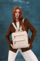 Mochila mediana de símil cuero color beige, con asa superior, dos compartimentos principales con cierre y dos bolsillos frontales con cierre. Las correas son ajustables y de color beige.