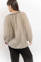 Blusa celeste de algodón con escote en V con lazos y mangas largas abullonadas con puños elásticos.
