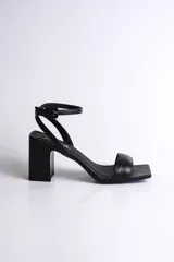 Sandalia de fiesta de cuero color negro, con diseño minimalista y pulsera al tobillo que asegura un calce firme. Tiene un taco cuadrado de 7,5 cm.