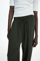Pantalón verde militar de viscosa, corte amplio, tiro alto, cintura elastizada con cordón de ajuste, bolsillos laterales y piernas rectas.
