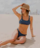 Conjunto de bikini azul con corpiño de breteles finos y hebillas metálicas en los tirantes. La bombacha es colaless y también tiene hebillas metálicas en los laterales.