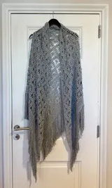Ruana de hilo de algodón color gris, tejida en crochet con diseño calado y terminación en flecos.