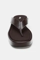 Sandalia plana color marrón con tira delantera para el dedo y suela con plataforma.