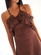 Vestido largo negro de lino, con breteles finos, espalda descubierta y tajo lateral. Presenta un volante de lino estampado en el escote.