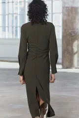 Vestido midi de cuello redondo y manga larga con puños. Tiene detalle de drapeado lateral y cierre trasero con cremallera oculta en la costura.