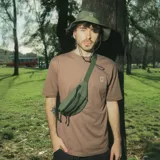 Sombrero negro tipo pescador, confeccionado en poliéster reciclado. Tiene ala mediana, ajuste elástico en la corona y tira ajustable con tanca.