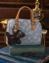 Cartera bowling de denim celeste con estampado de flores blancas, doble asa corta de cuero marrón y correa larga regulable y desmontable.